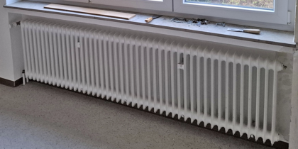 Großer Heizkörper mit Schrauben, Spachtel und Brettchen auf Fensterbank