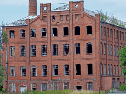 Altes Fabrikgebäude aus rotem Backstein mit kaputten Fenstern