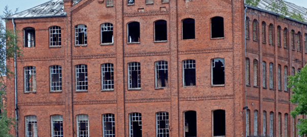 Altes Fabrikgebäude aus rotem Backstein mit kaputten Fenstern